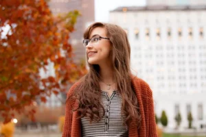 Young woman with glasses and braces standing outside smiling