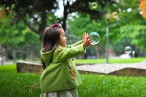 little girl grabbing bubble outside